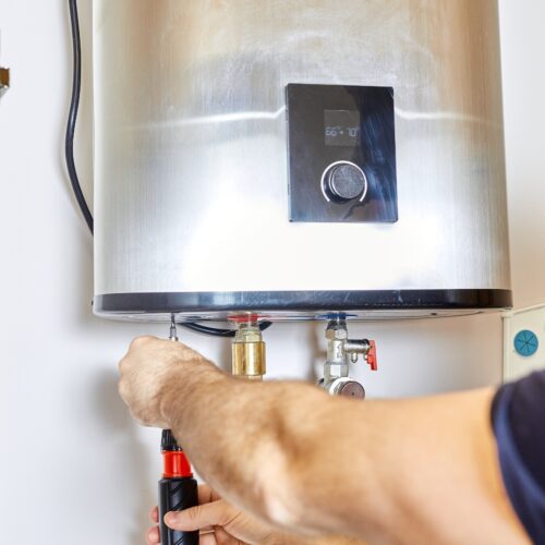 Man,Tightens,The,Pipe,Nut,In,The,Water,Heating,System.